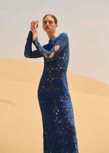 a woman standing in the desert wearing a blue dress