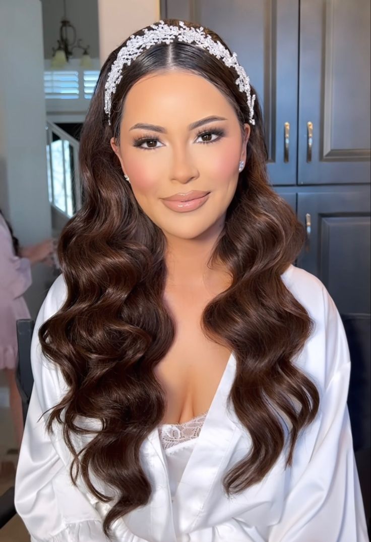 a woman with long brown hair wearing a white dress and headpiece on her head