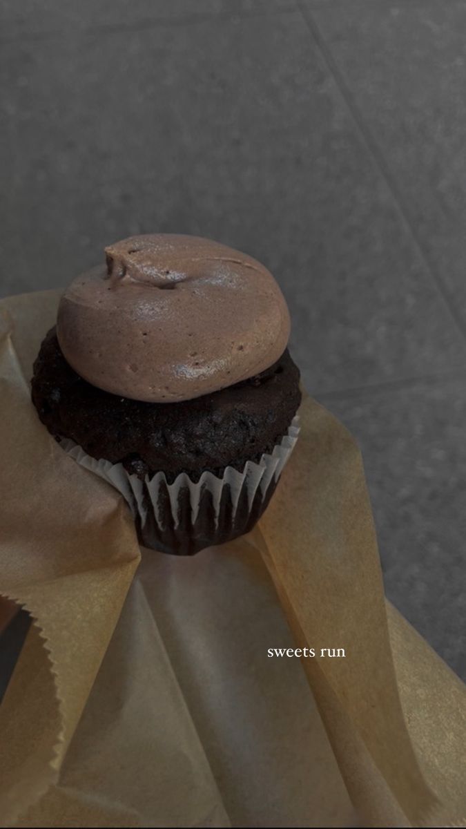 a chocolate cupcake sitting on top of a brown paper bag