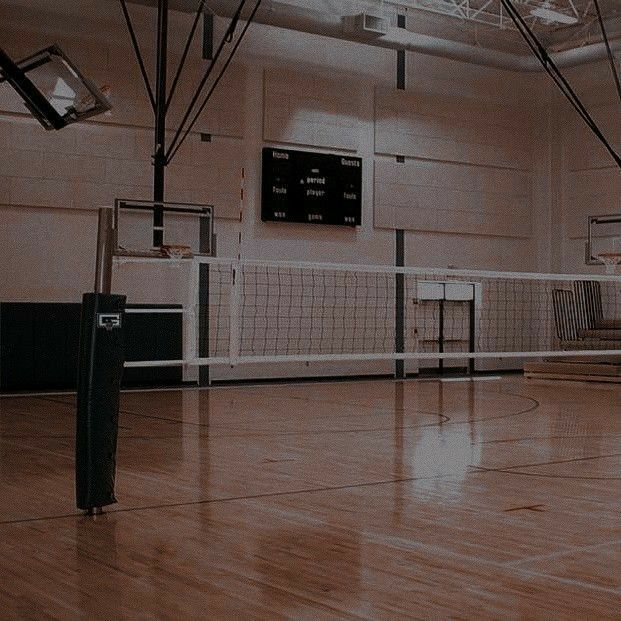 an indoor volleyball court with net and ball in the middle, on hard wood flooring