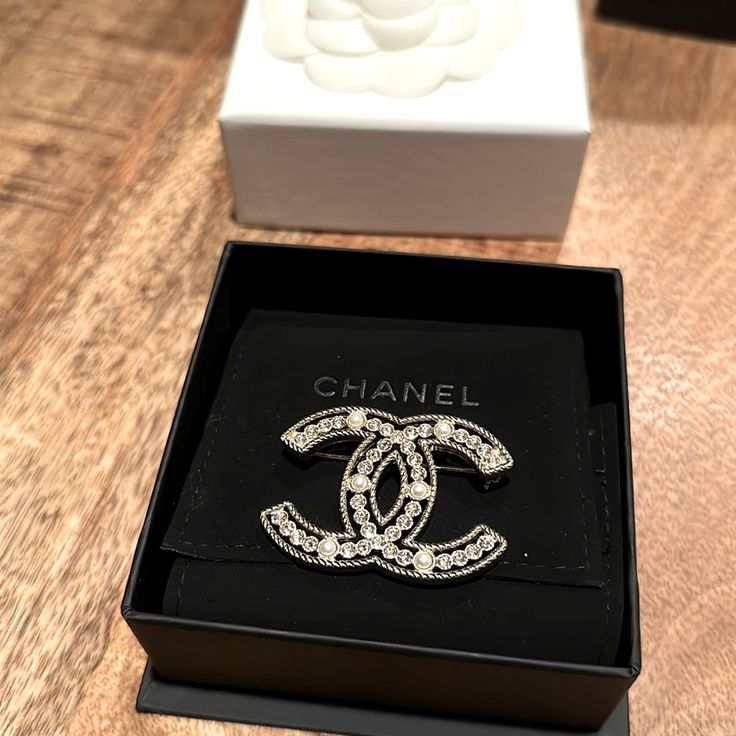 Preowned. In Original Box. Excellent Condition. Limited Edition Chanel Brooch. 6 Pearls And 38 Rhinestones. Luxury White Gold Brooches With Diamond Accents, Classic White Diamond Brooches, Luxury Diamond Brooches In White Gold, Luxury Diamond White Brooch As Gift, Luxury White Gold Diamond Brooches, Classic White Brooches For Evening, Luxury Diamond White Brooches For Anniversary, Classic White Evening Brooches, Luxury Crystal Embellished Jewelry As Gift