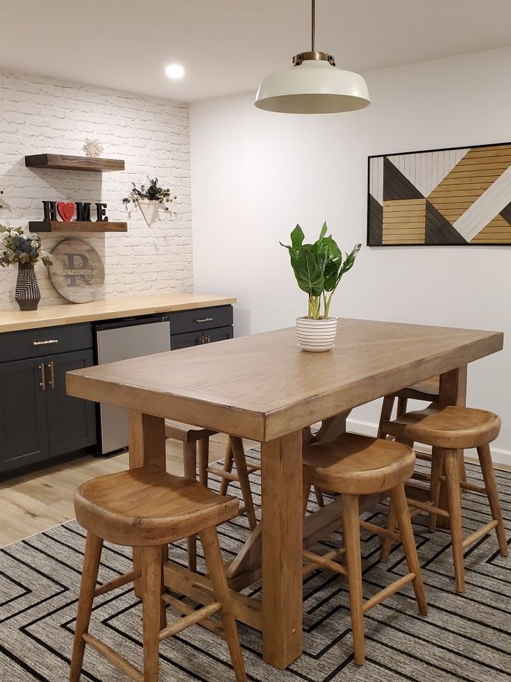 a dining room table with four stools and a potted plant on the counter