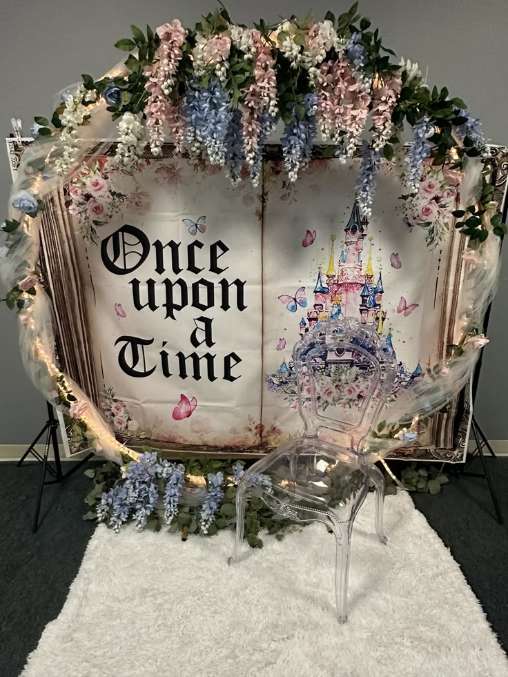 an open book decorated with flowers and fairy land is displayed on a white rug in front of a gray wall