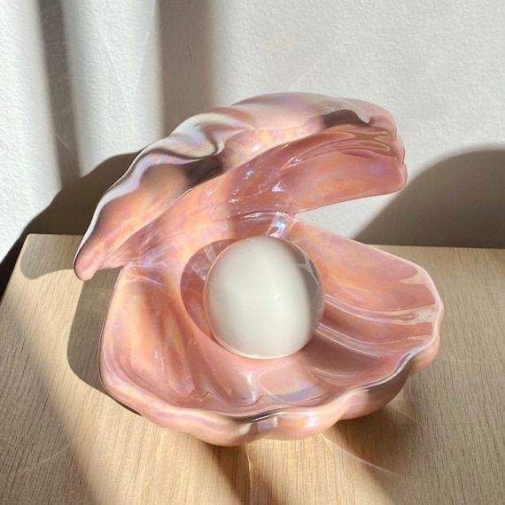 a pink glass object with a white ball in the center sitting on a wooden table