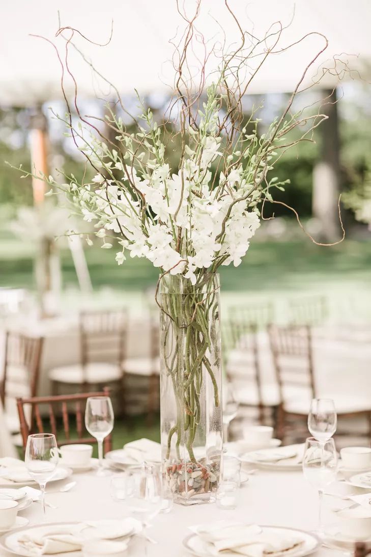 a vase filled with white flowers sitting on top of a table covered in plates and glasses