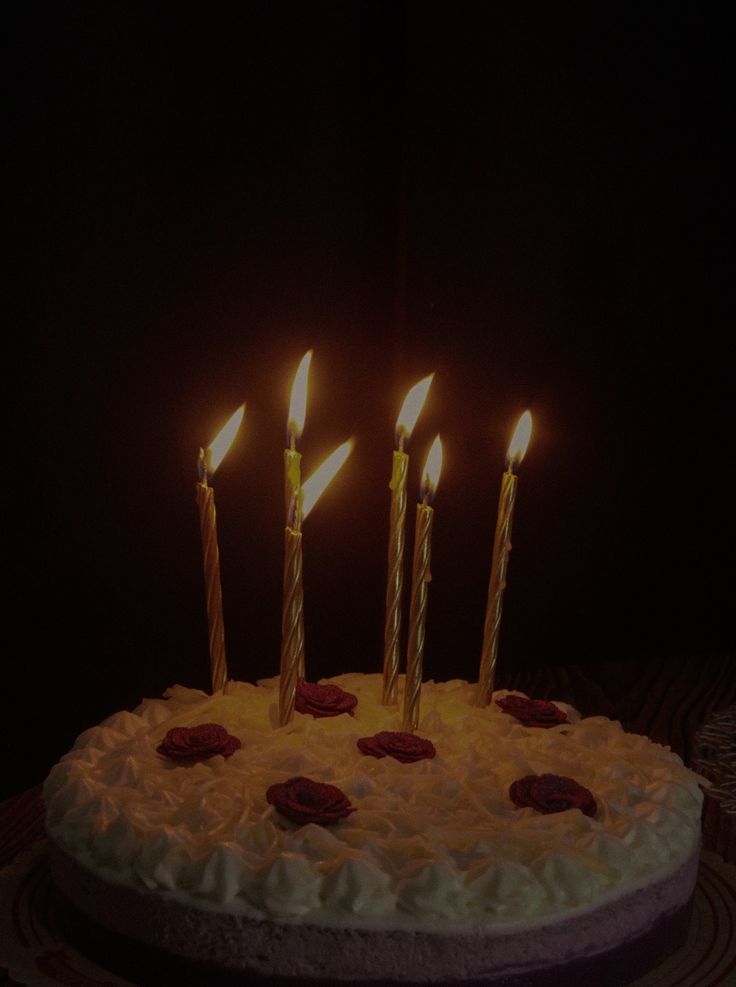 a birthday cake with five lit candles on it