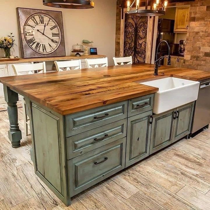 a large kitchen island with a sink and wooden counter tops in front of a clock