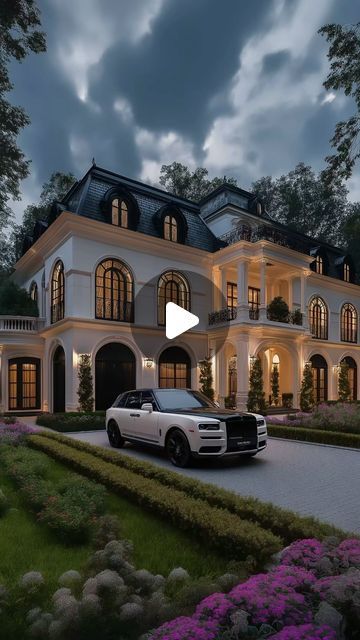 a white car parked in front of a large house at night with the lights on