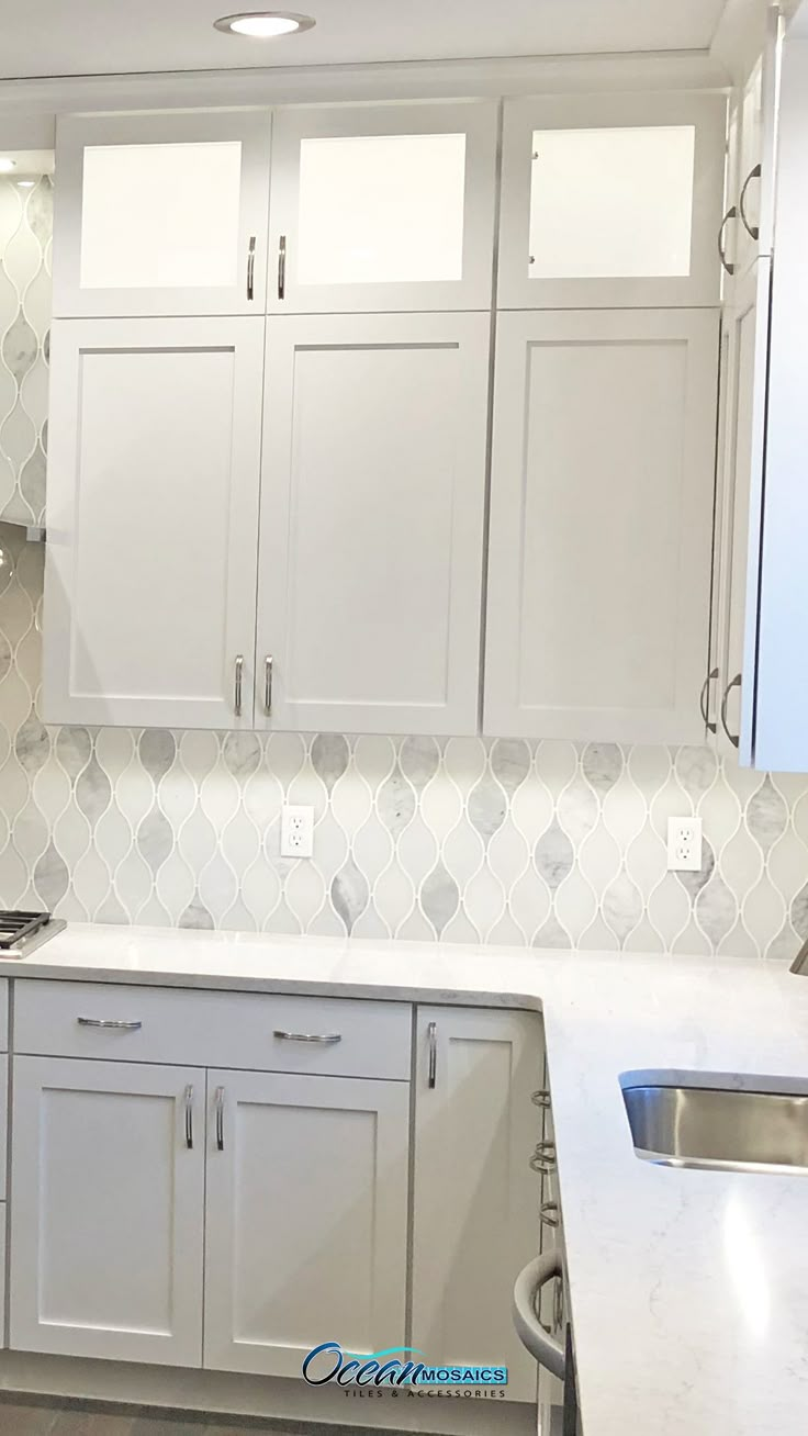 a kitchen with white cabinets and marble counter tops