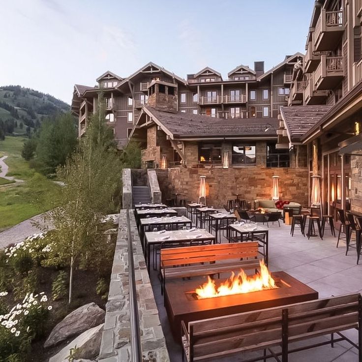 an outdoor patio with tables and chairs next to a fire pit in front of a building