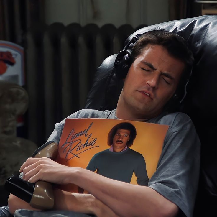 a man laying on a couch holding an autographed photo with his head resting on a pillow