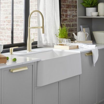 a white kitchen sink sitting under a window next to a counter top with dishes on it