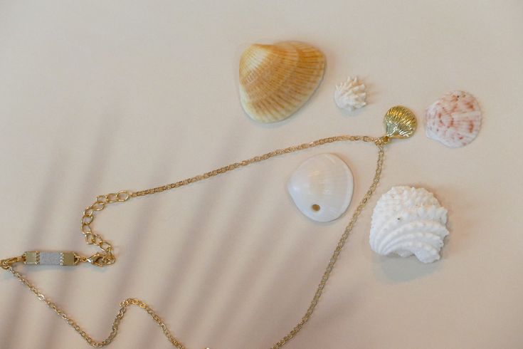 Embrace the beauty of the sea with the Summer Ocean’s Shell Necklace. This enchanting piece features a finely detailed shell pendant, perfect for adding a touch of ocean-inspired elegance to any outfit. Ideal for both casual beach days and sophisticated summer evenings, this necklace brings the serenity of the ocean to your wardrobe. Details Alloy material 14.5” chain , 2” extension extender option and a 1” dainty diffuser extender. Dainty diffuser for diffusing essential oils which can be removed if desired. Unique faux suede material will diffuse essential oils for hours. Wipe your necklace clean after wearing to preserve the life of your jewelry. Please keep dry and remove when bathing or swimming. Ocean-inspired Pearl Pendant Jewelry, Elegant Starfish Charm Jewelry For Vacation, Elegant Beach Jewelry With Pearl Pendant, Beach Pendant Jewelry With Clavicle Chain, Elegant Pearl Charm Strand Jewelry, Beach Jewelry: Pearl Charm Pendant, Beach Pendant Jewelry With Pearl Charm, Beach Pearl Charm Pendant Jewelry, Gold Shell Necklace With Starfish Charm On Strand