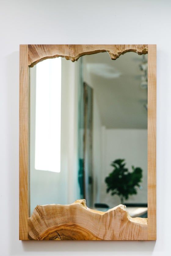 a wooden mirror hanging on the wall