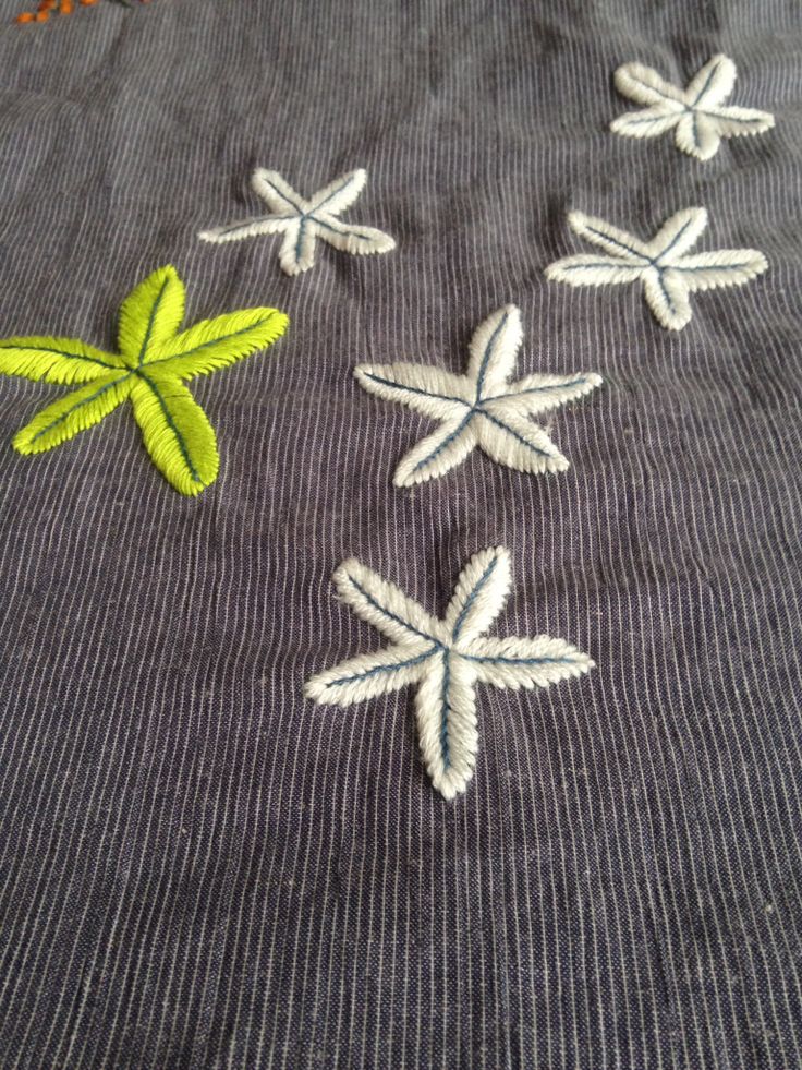 four embroidered stars on a piece of gray fabric with green and white trimmings