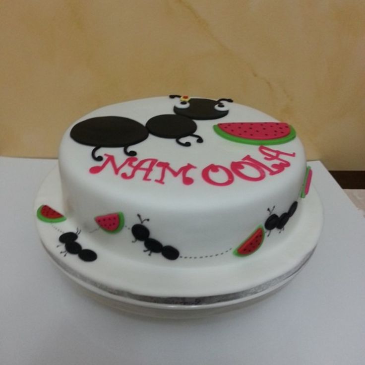 a white cake decorated with ladybugs and watermelon