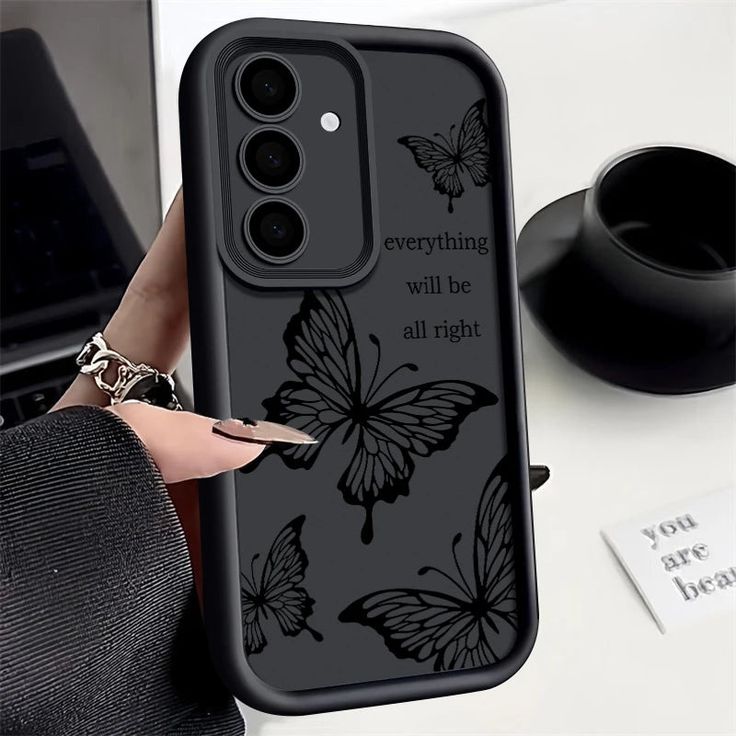 a woman is holding up her phone case with butterflies on it and the words everything will be all right