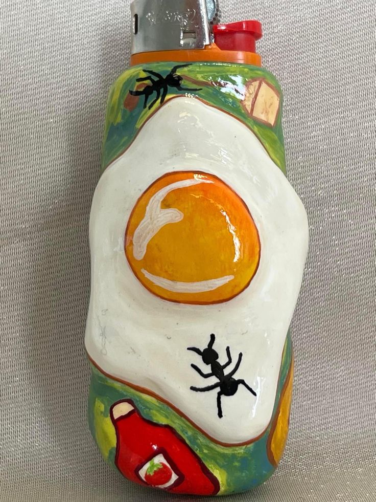 a ceramic bottle with an egg and spider painted on it