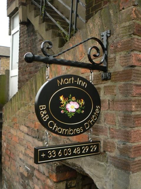 a black sign hanging from the side of a brick building