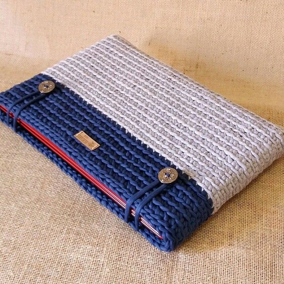 a blue and white knitted case sitting on top of a beige cloth covered table