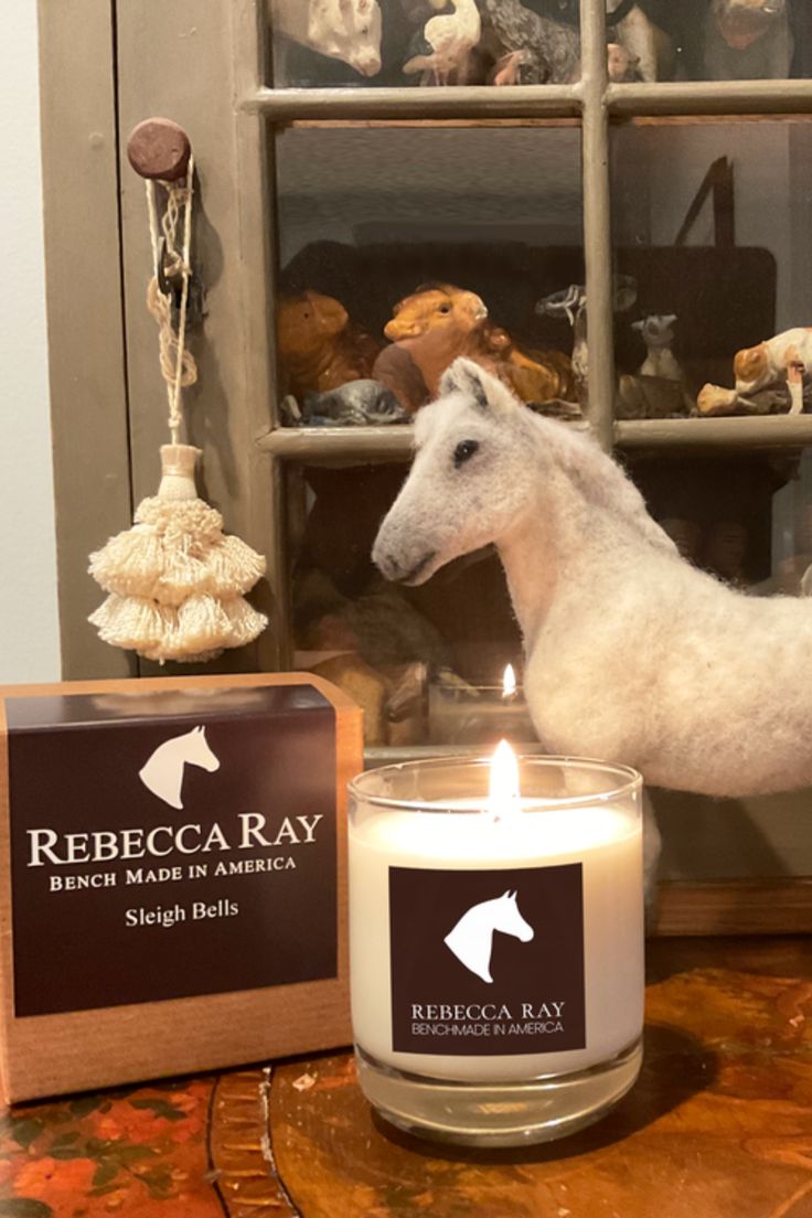 a white horse figurine next to a candle on a table with other items