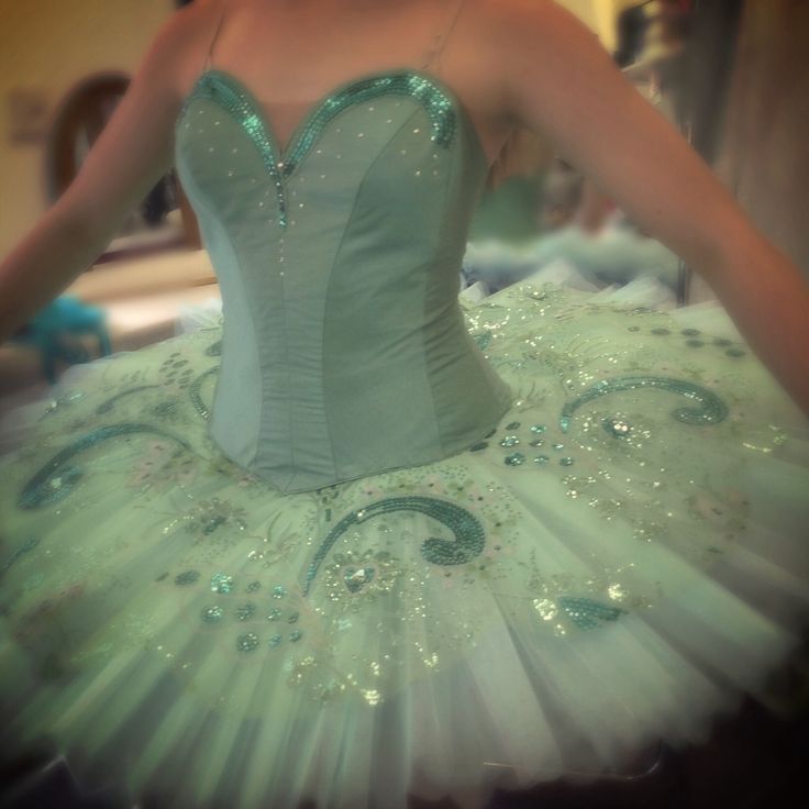 a woman wearing a green and white ballerina tutu with sequins on it