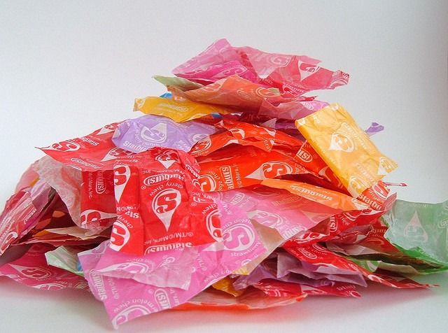 a pile of colorful candy wrappers sitting on top of a white table next to each other