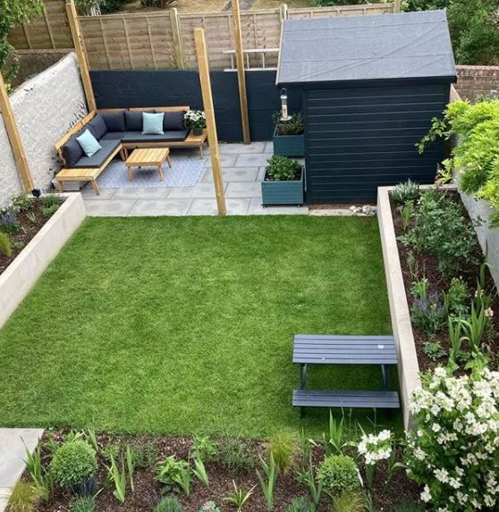 a small backyard garden with green grass and wooden benches