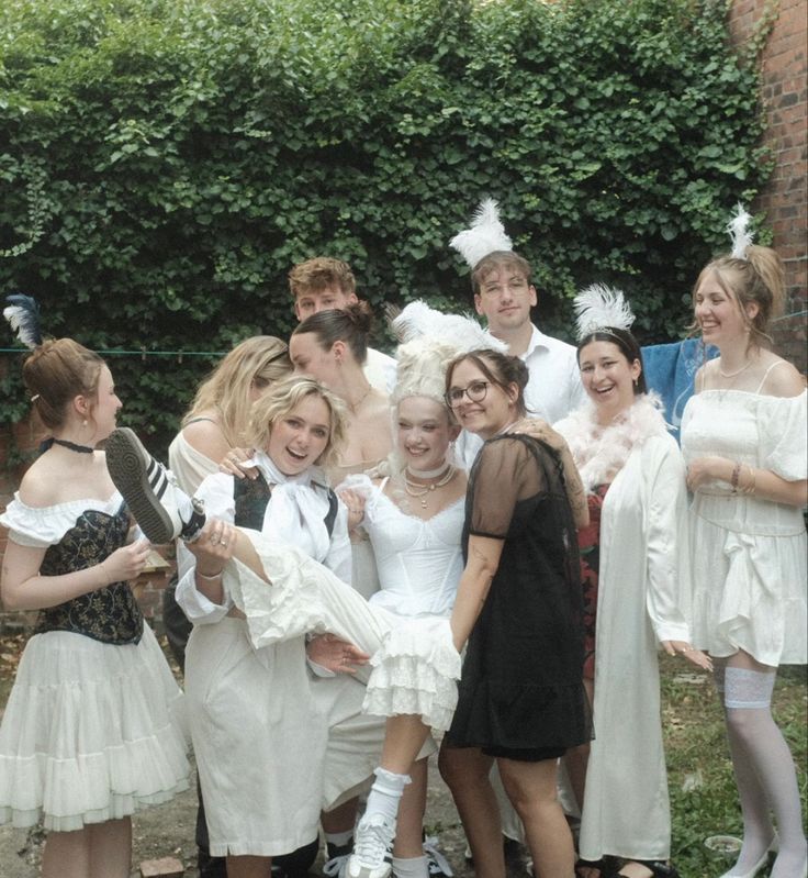 a group of people standing next to each other in front of a fence and bushes