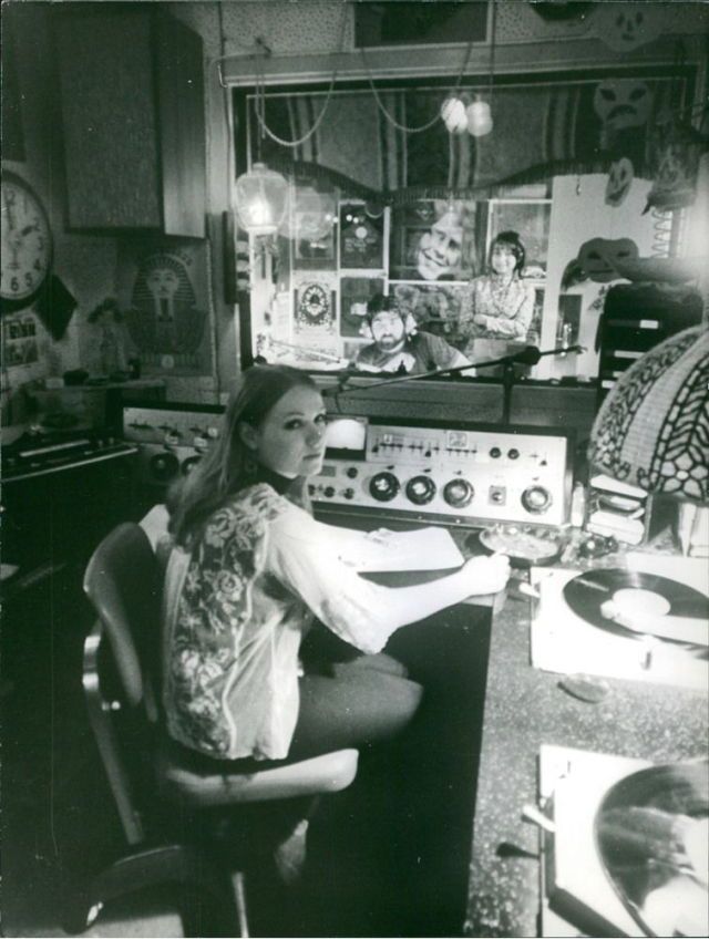 a woman sitting at a desk in front of a radio