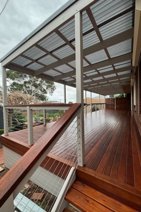 a wooden deck with metal railings next to a house