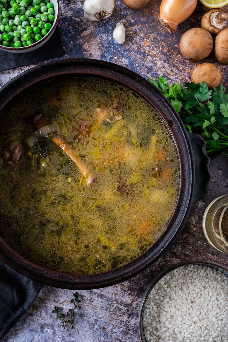 a large pot filled with soup next to some vegetables and other food on a table