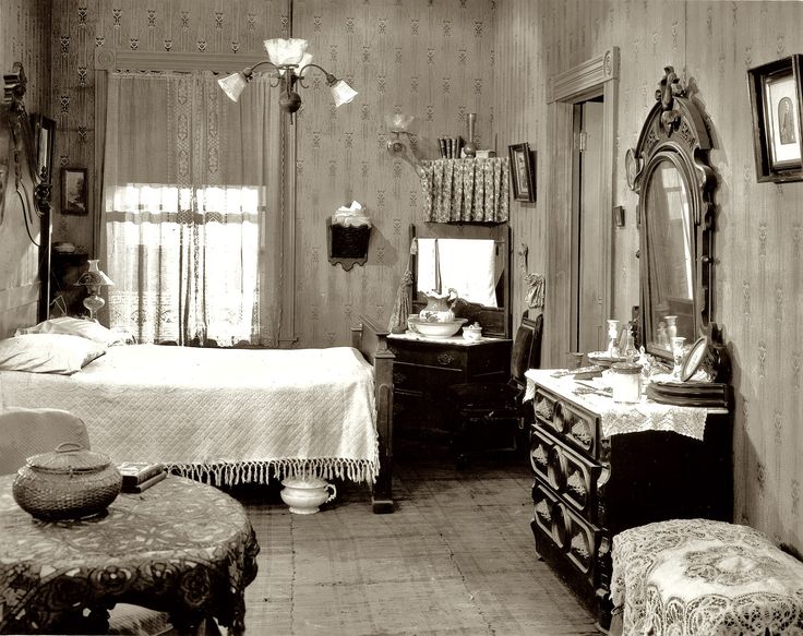 an old black and white photo of a bedroom with a bed, dresser, mirror and chair