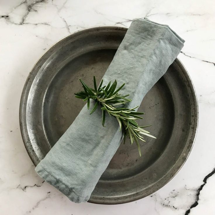 a plate with a napkin on it and a sprig of rosemary in the middle