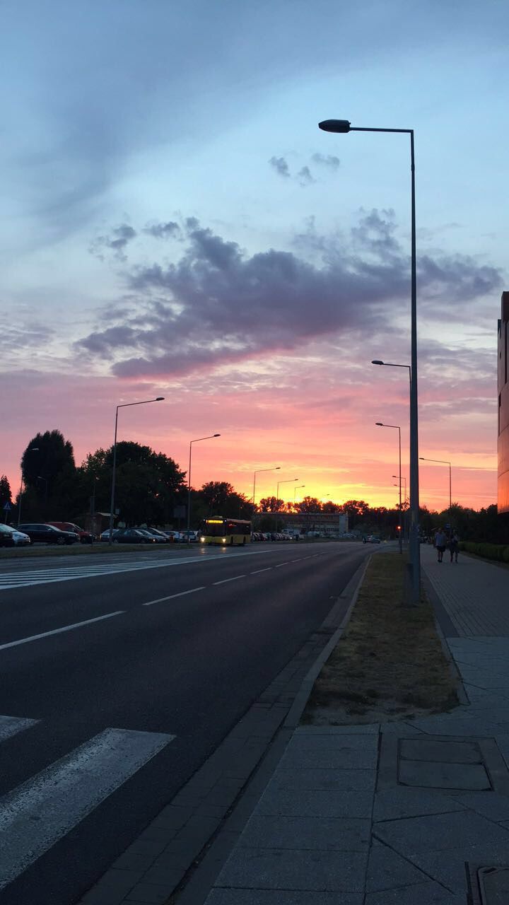 the sun is setting over an empty street