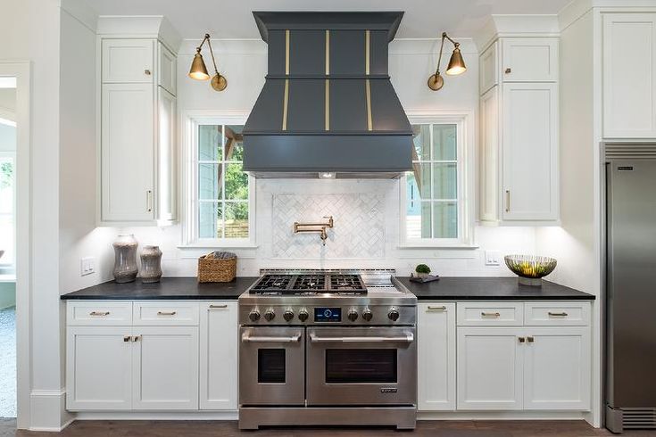 a stove top oven sitting inside of a kitchen next to white cabinets and counter tops