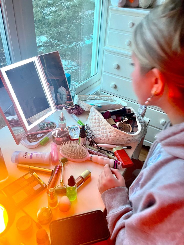 a woman sitting at a desk in front of a computer monitor with makeup on it