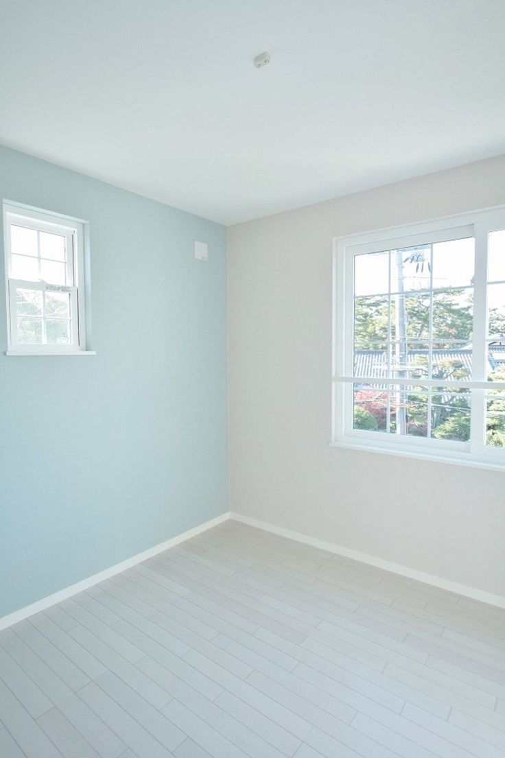 an empty room with two windows and hard wood flooring on one side, white tile on the other