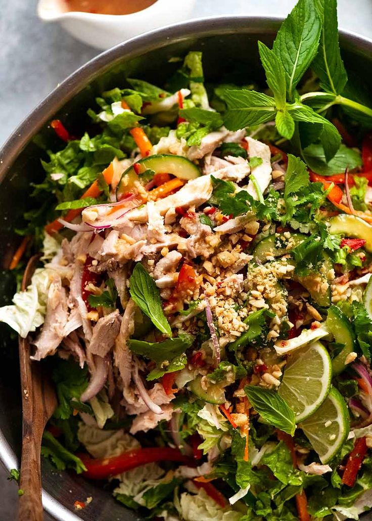 a salad with chicken, lettuce, carrots and other vegetables in a bowl