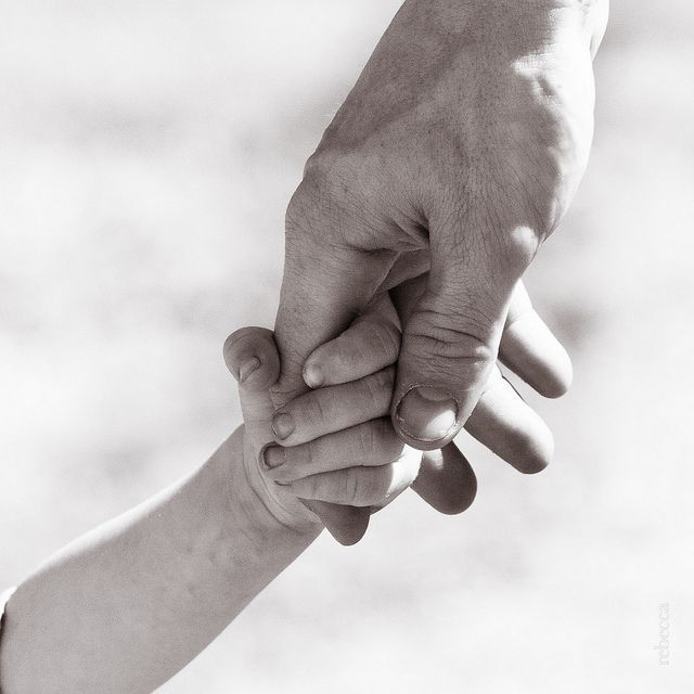 an adult holding the hand of a child's hand in black and white photo