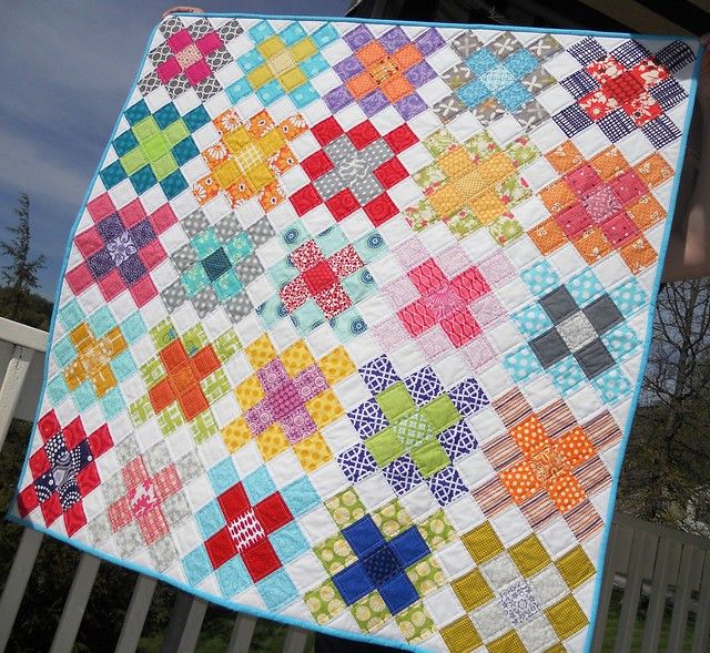 a person holding up a colorful quilt