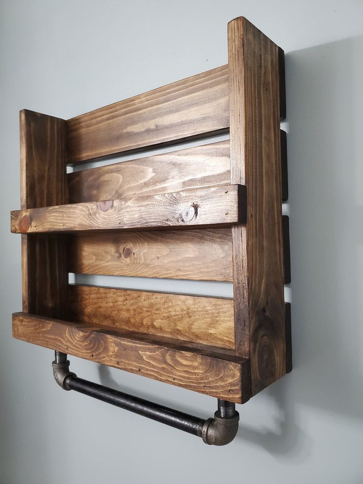 a wooden shelf mounted to the side of a wall with pipes on both sides and two shelves above it