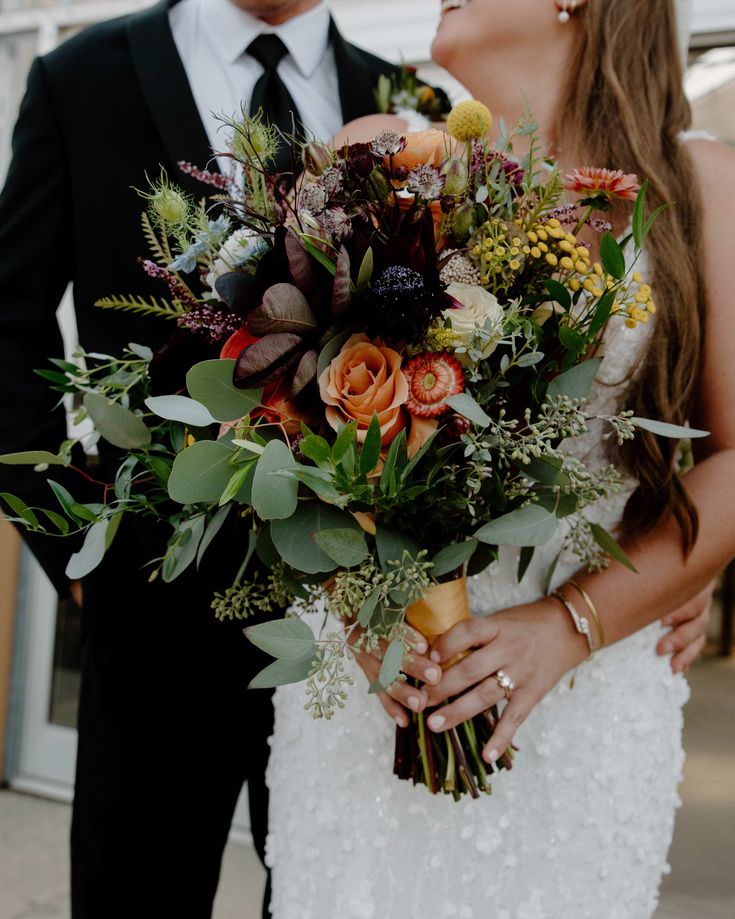 the bride and groom are standing together holding their bouquets in front of each other