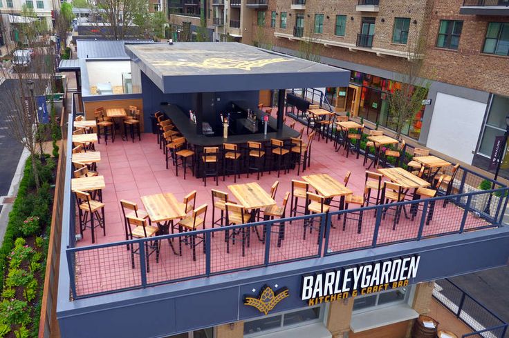 an overhead view of a patio with tables and chairs in the center, surrounded by tall buildings