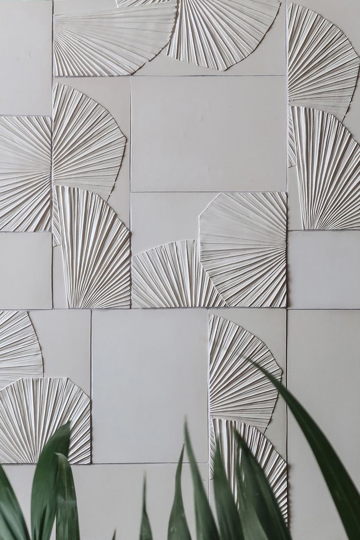 a white tiled wall with palm leaves on it