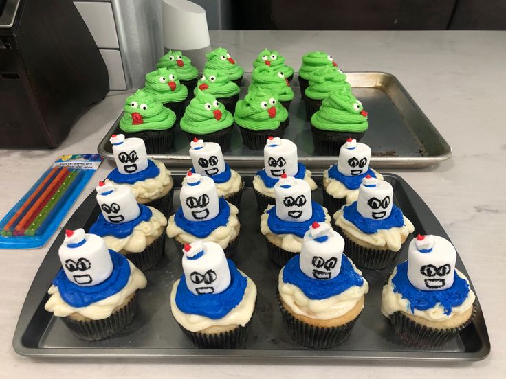 cupcakes with green and blue frosting are arranged on a tray next to other cupcakes