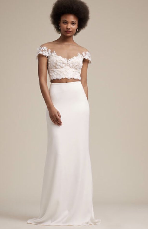 a woman in a white dress with an off the shoulder crop top and long skirt