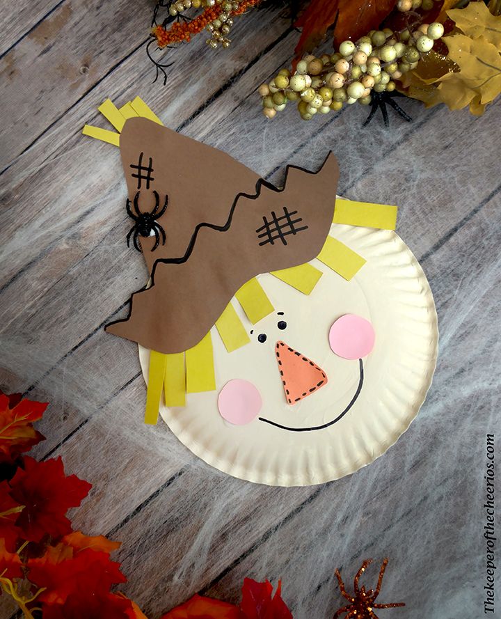 a paper plate with a scarecrow on it next to fall leaves and pumpkins