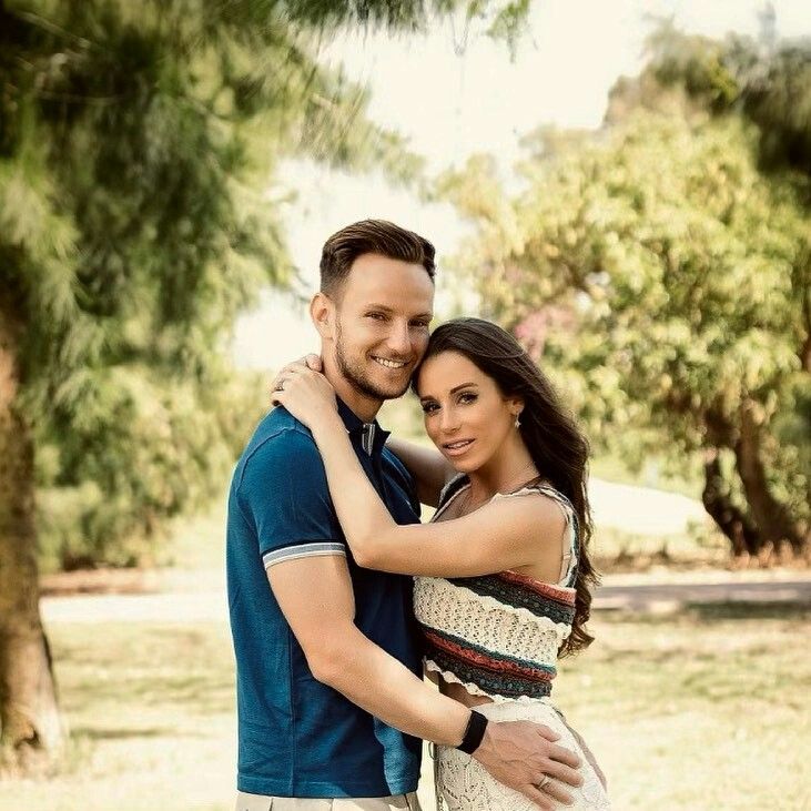 a man and woman hugging each other in the grass with trees in the back ground