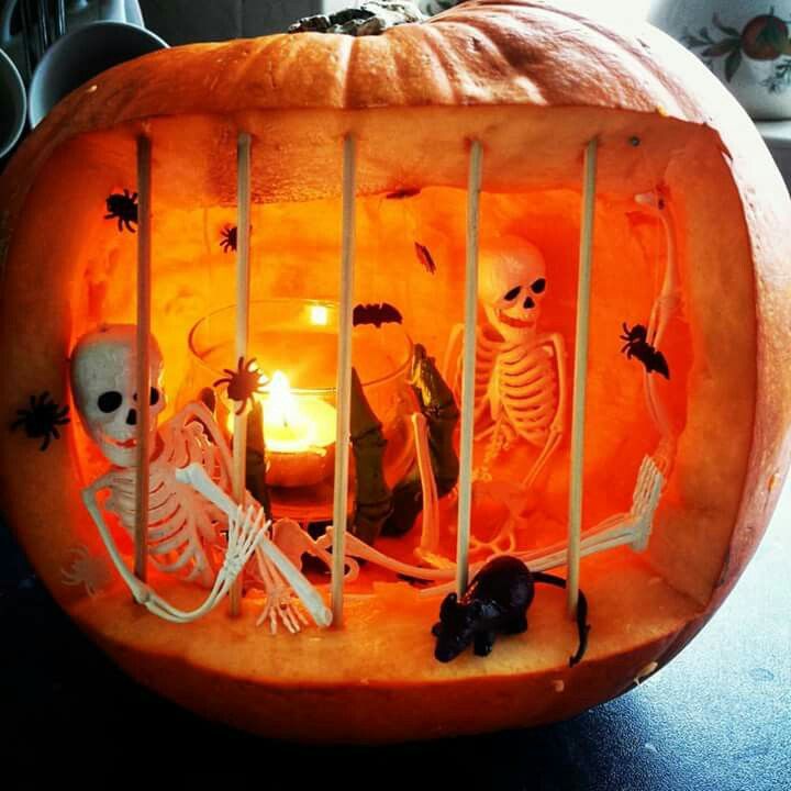 a carved pumpkin with skeletons and candles inside